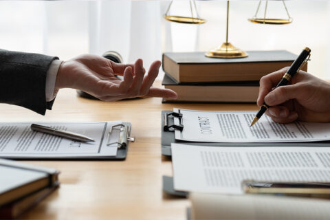 deux personnes se faisant face, l'un signant des documents